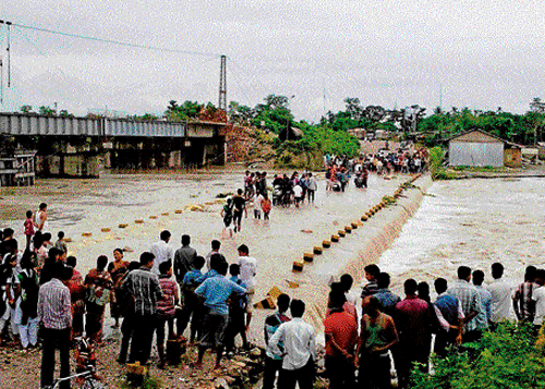 People move through a flooded road after heavy rains in Alipurduar in West Bengal on Monday. PTI