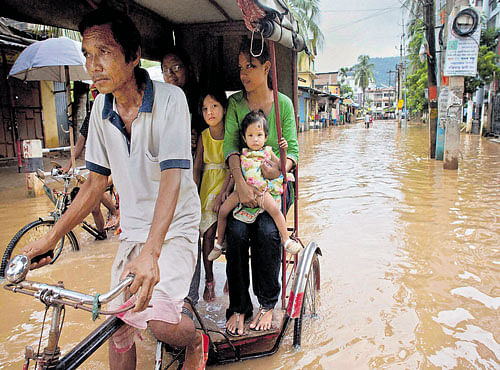 Commuters ride a cycle rickshaw after rain flooded the area in Guwahati on Sunday. PTI