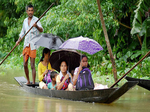 : A flood affected family travel on a boat to a safer area in Kolakhowa, Assam on Monday.PTI Photo