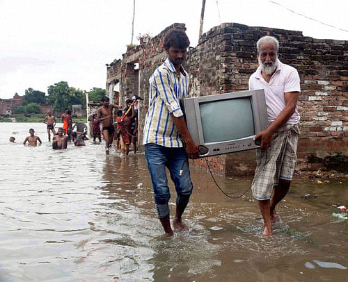 Resident move with their belongings after flood in Ganga and Varuna river in Varanasi on Thursday. PTI Photo
