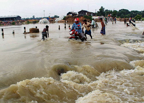 Villagers wade though the flooded Burdwan-Katwa road at Norjai Setu in Burdwan district of West Bengal on Tuesday. PTI Photo