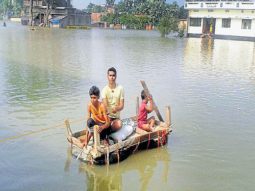 People use a home-made boat along a flooded village in Chapra, Bihar on Wednesday. PTI