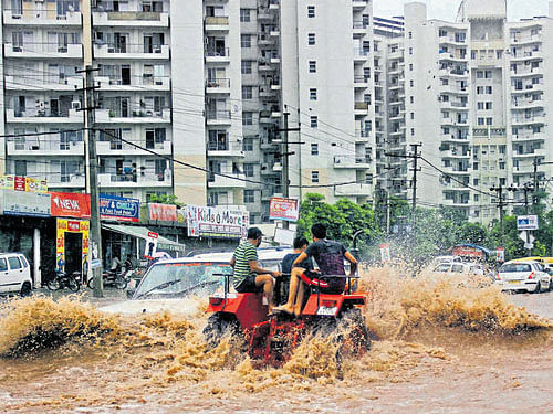 Vehicles wade through a waterlogged road at Palam Vihar after heavy rain in Gurgaon on Thursday. PTI