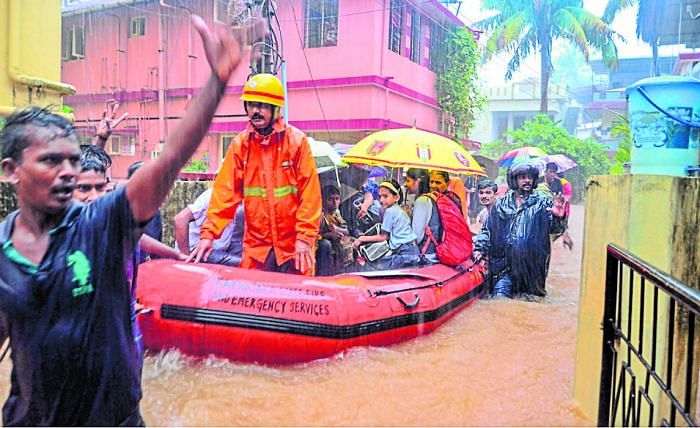 Rescuers shift school children to a safer place from a flooded locality, after a thunderstorm in Mangaluru on Tuesday. PTI
