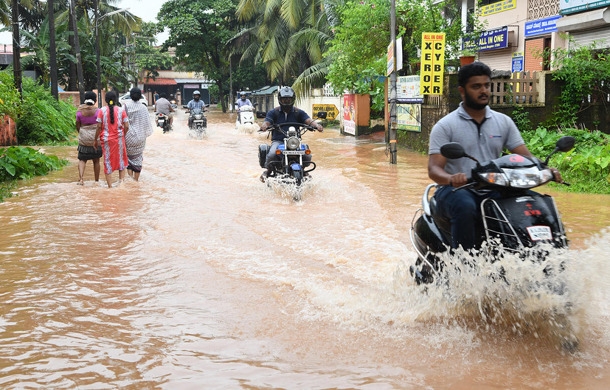 Motorcyclists navigate a flooded road at Malemar on Friday.