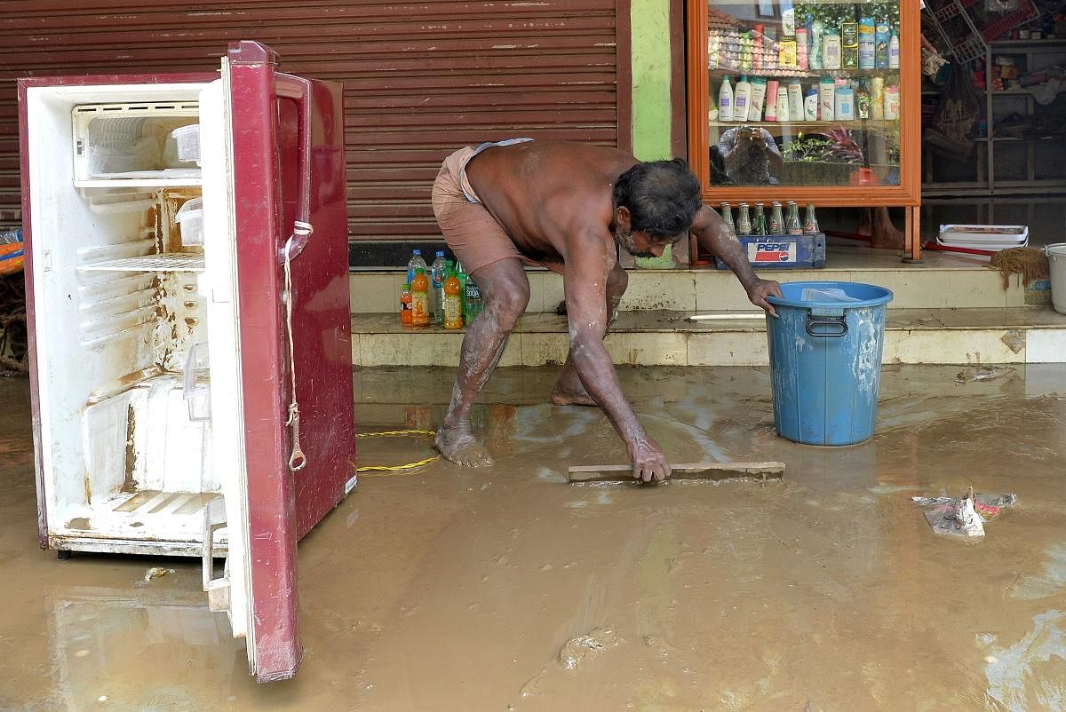 An Indian shopkeeper cleans out a muddy shop after flood waters receded in Pandanad in Alappuzha District in the south Indian state of Kerala. (AFP photo)