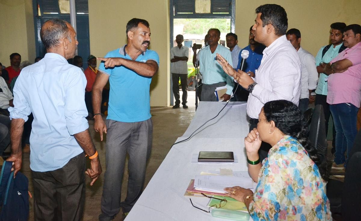 Flood victims argue with Special Additional Deputy Commissioner Jagadish at a grievance meeting held atKaveri Kalakshetra in Madikeri on Tuesday.