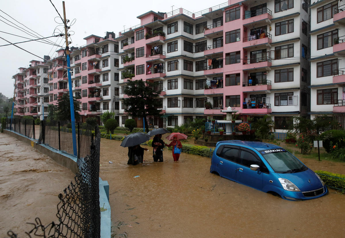 Residents walk towards dry ground from a flooded colony in Kathmandu, Nepal. (Reuters Photo)