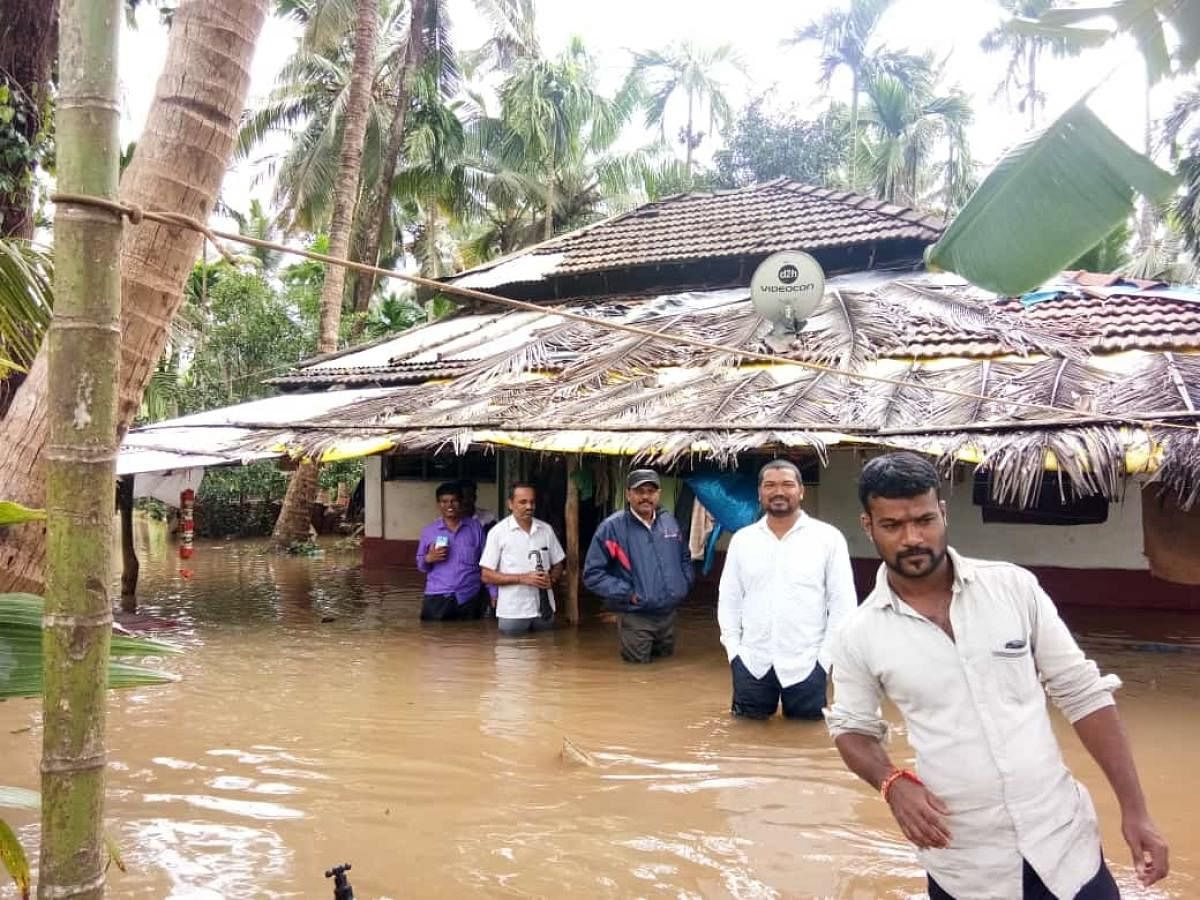 People from Jalavalli Holebadikeri village in Honnavar taluk in Uttara Kannada district move to safety after their houses were flooded. DH Photo