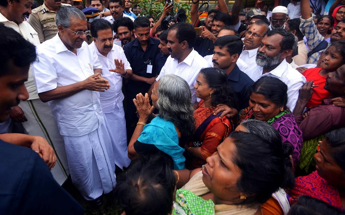 Kerala chief minister Pinarayi Vijayan (L) along with opposition leader Ramesh Chennithala (2L) visit relief camp in Chengamanadu Government Higher Secondary School (HSS) in Ernakulam district. AFP photo.
