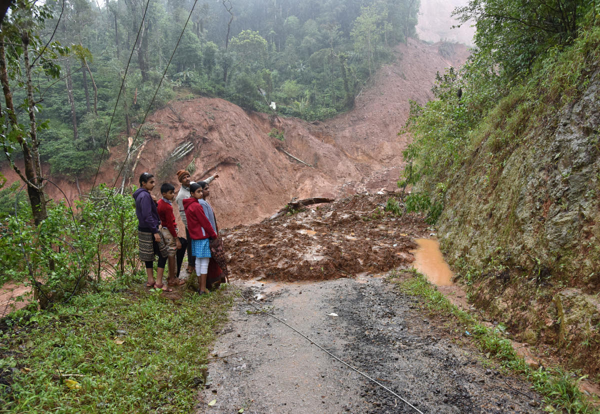 The Poovaiah family shows the part of the hill that collapsed and destroyed their house in Chappe, Hebbettageri, Madikeri on Thursday. Photo/ B H Shivakumar