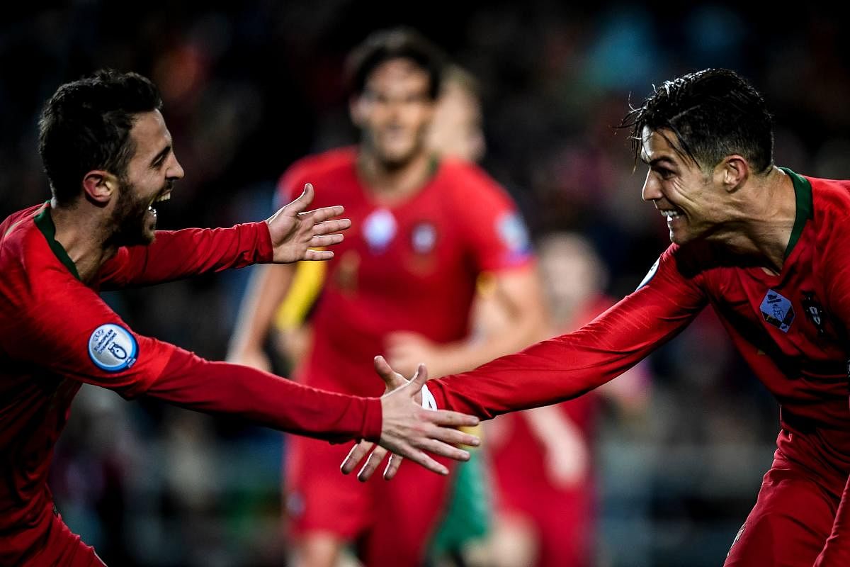 Portugal's forward Cristiano Ronaldo (R) celebrates with his teammate Portugal's forward Bernardo Silva (L) after scoring during the Euro 2020 Group B football qualification match between Portugal and Lithuania at the Algarve stadium in Faro, on November 14, 2019. (Photo by AFP)