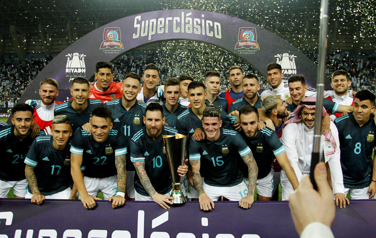 Argentina's Lionel Messi poses with a trophy and teammates as they celebrate after the match. Reuters