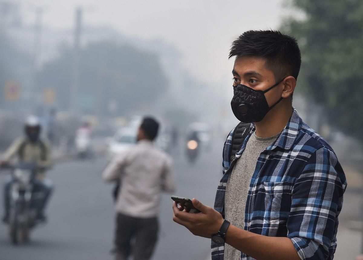 A tourist wears an anti-pollution mask amid heavy smog as the air quality further dips to 'severe' category, in New Delhi.  (PTI Photo)
