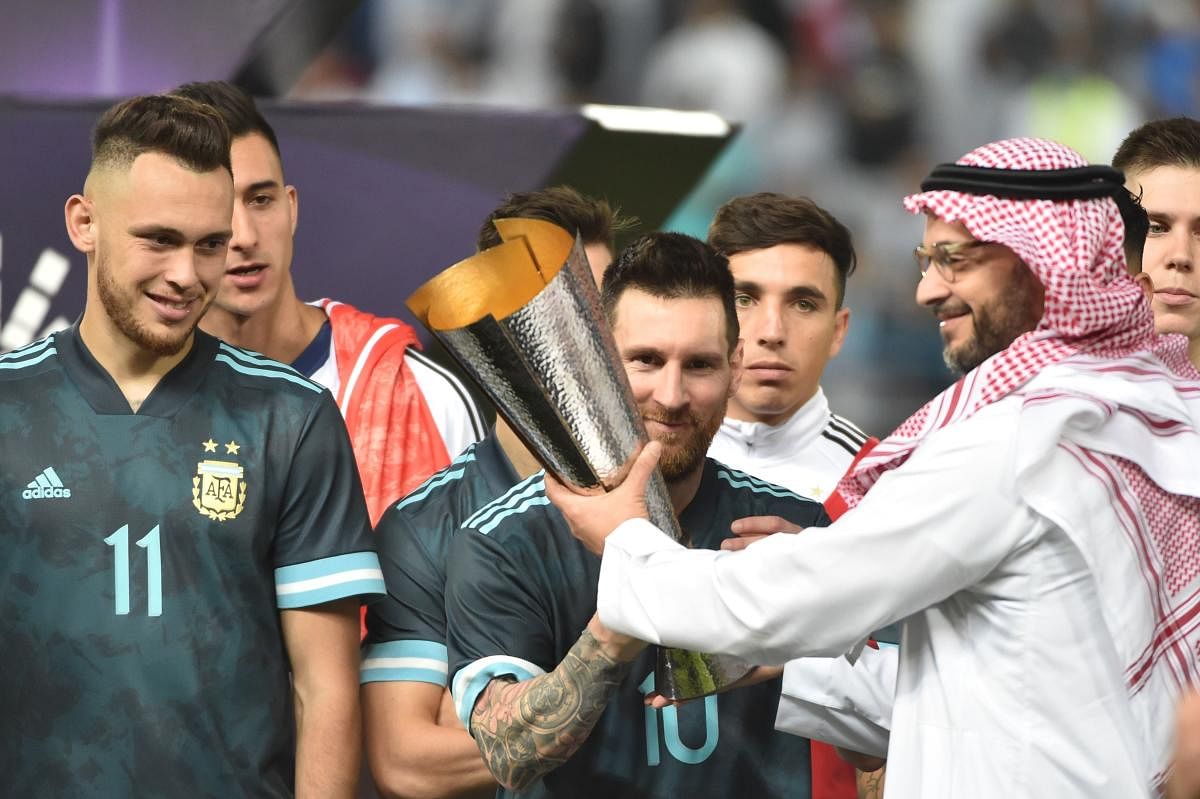 Argentina's forward Lionel Messi is presented with a cup after their win during the friendly football match between Brazil and Argentina at the King Saud University stadium in the Saudi capital Riyadh. (Photo by AFP)