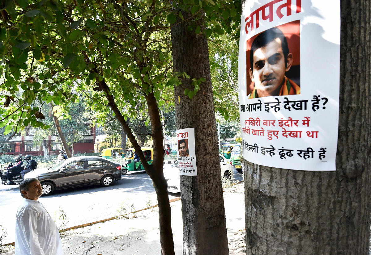 A man looks at posters of BJP MP Gautam Gambhir, put up after he failed to attend a key meeting on pollution called by a parliamentary panel, in New Delhi. (PTI Photo)