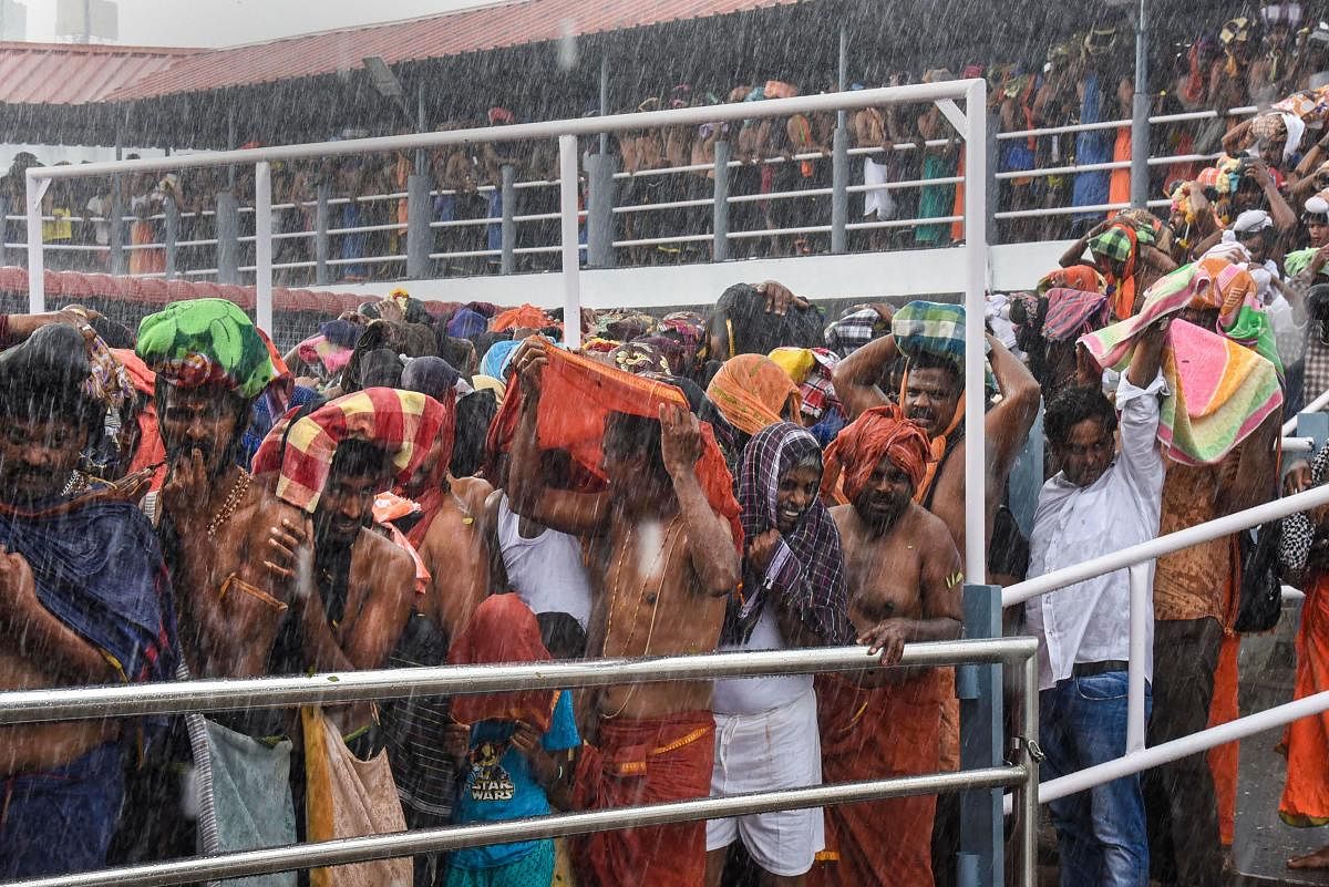 Devotees stand in queues during rainfall to offer prayers at Lord Ayyappa temple on the 1st day of Malayalam month of 'Vrischikom,' in Sabarimala, Sunday, Nov. 17, 2019. (PTI Photo)