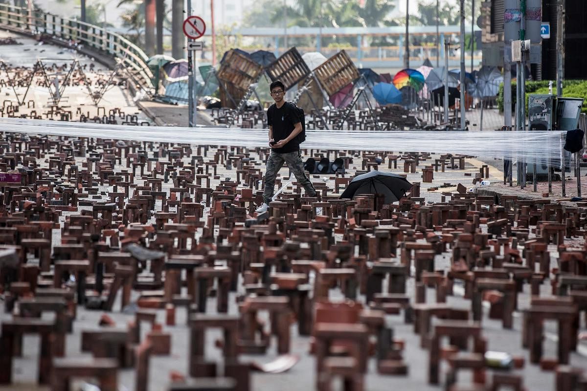 A man walks through bricks placed on a barricaded street outside The Hong Kong Polytechnic University in Hong Kong on November 15, 2019. - Pro-democracy protesters challenging China's rule of Hong Kong on November 14 choked the city for a fo