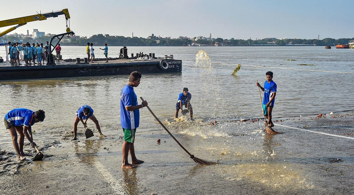 Municipal workers clean the ghat on the bank of River Ganga to prevent pollution. (PTI Photo)