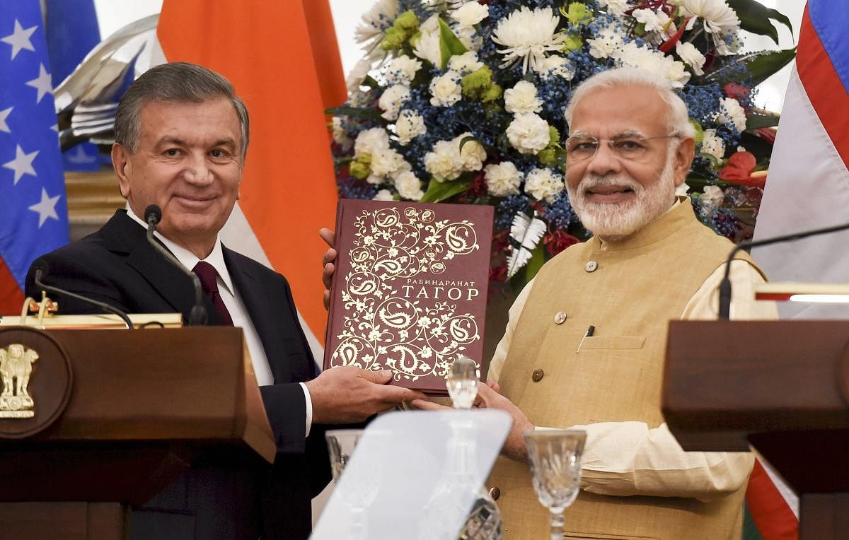 Prime Minister Narendra Modi is presented a book by Uzbek President Shavkat Mirziyoyev look on, at Hyderabad House in New Delhi on Monday. PTI