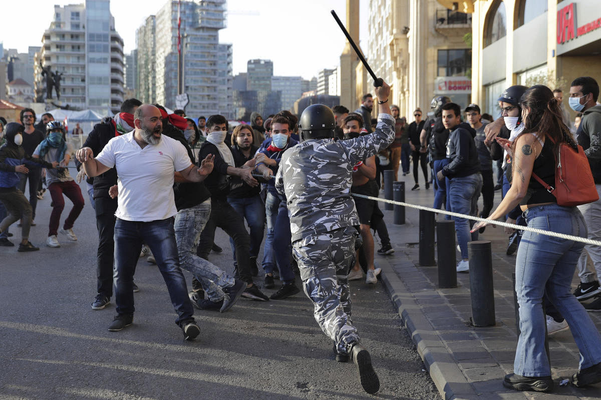 A police officer raises his baton to anti-government protesters during clashes during a protest in downtown Beirut, Lebanon. (AP/PTI Photo)