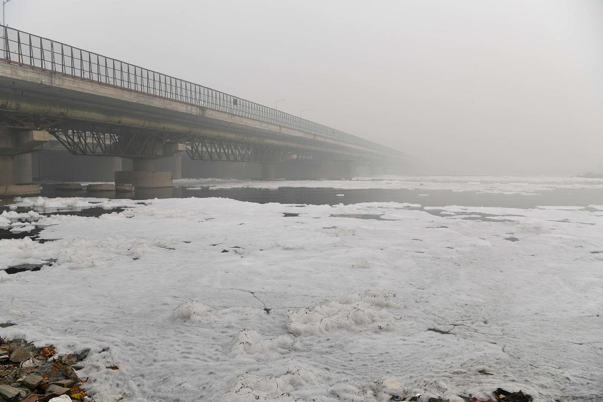 Foam is seen floating along the Yamuna river near a bridge amidst heavy smog conditions, in New Delhi. AFP