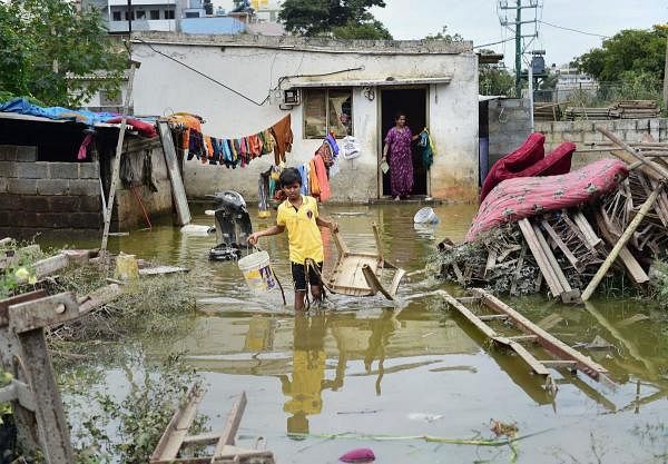 A boy walks through flood water outside his house after a breach in the Hulimavu Lake, in Bengaluru, Monday, Nov 25, 2019. (PTI photo)