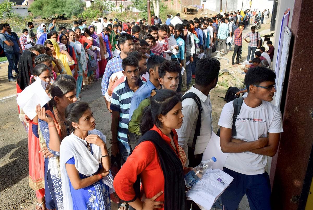 Applicants for Uttar Pradesh Police Constable Recruitment wait in a queue outside their exam centre, in Allahabad on Monday. (PTI Photo)