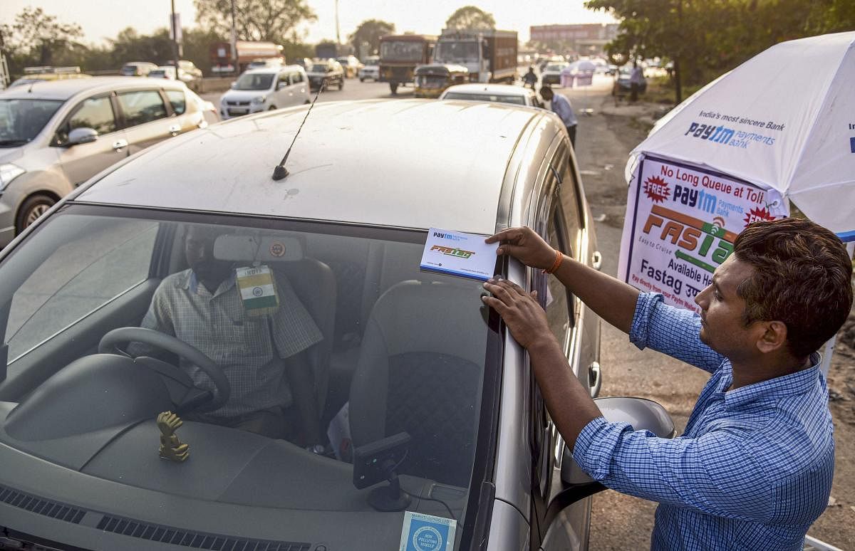  A worker fixes a FASTag sticker on the windscreen of a car. (PTI Photo)