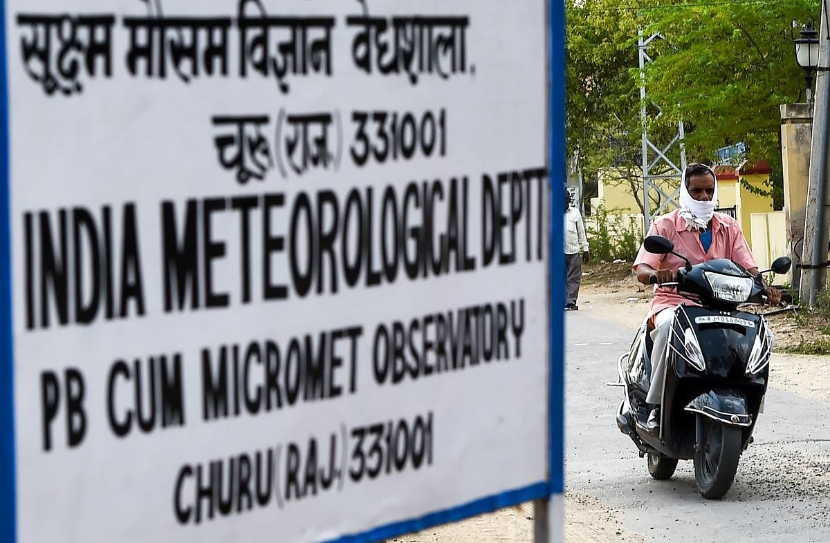 An Indian man rides a scooter as he covers his face to protect himself from the heat outside the India Meteorological Department office in Churu in Rajasthan on June 3, 2019. (AFP Photo)