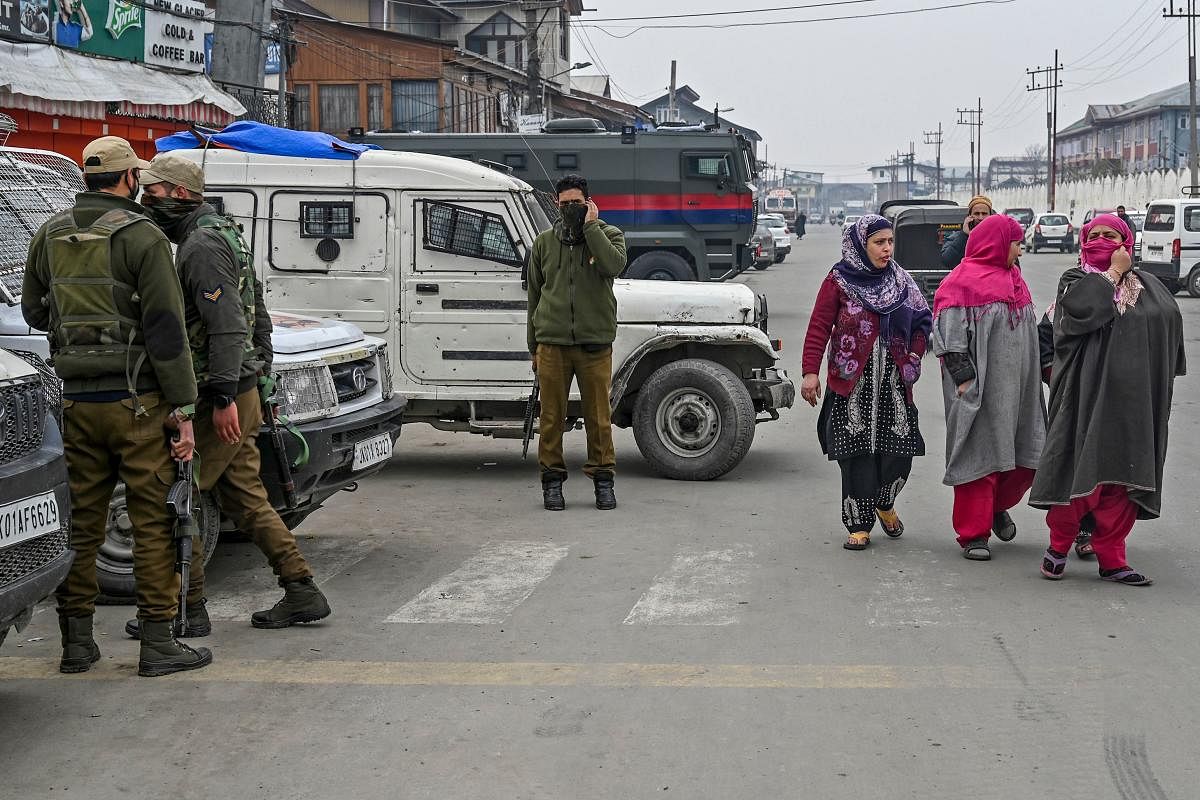 Security personnel stand near the site of a grenade blast as residents walk on a roadside at a market place outside the campus of Kashmir's main university in Srinagar on November 26, 2019. (AFP Photo)
