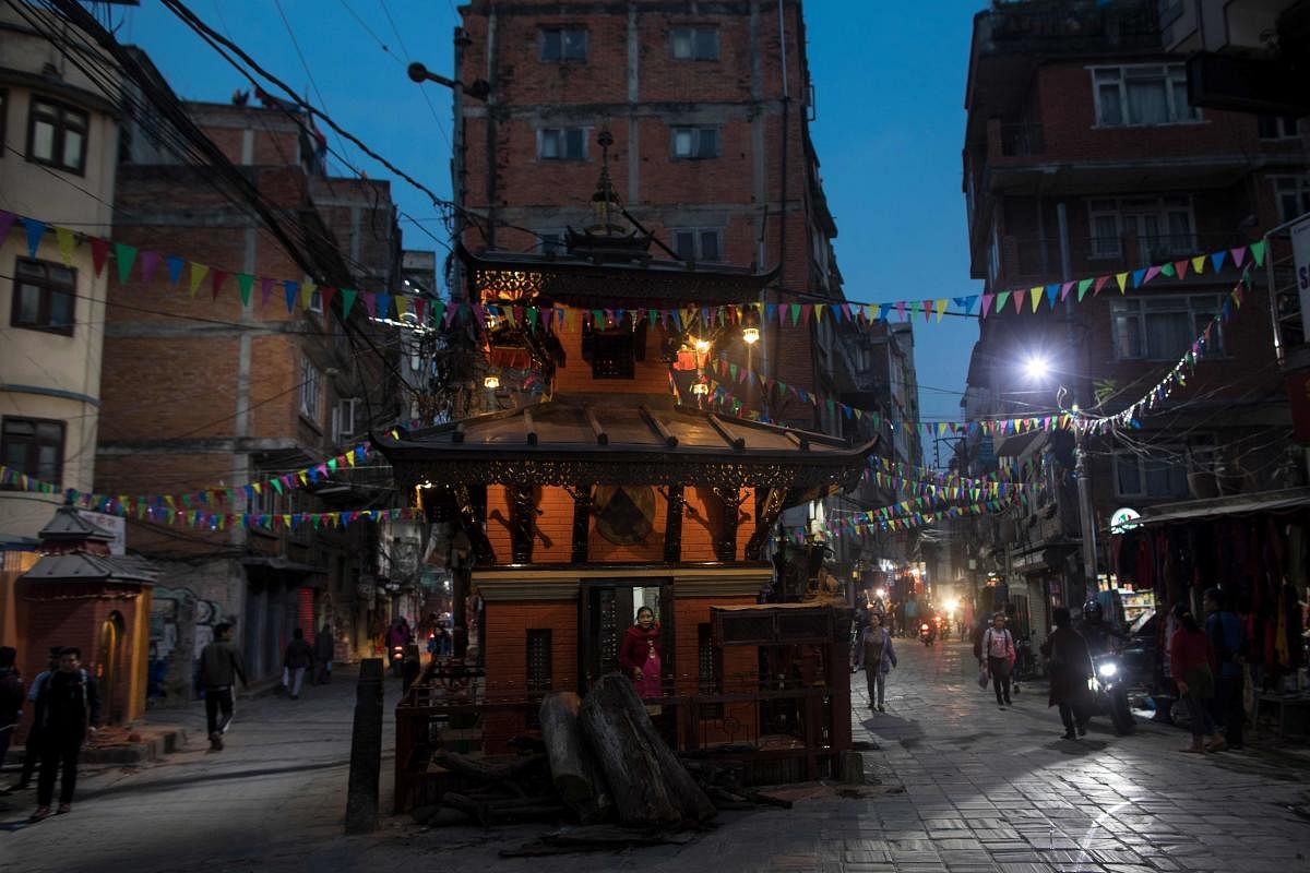 A devotee looks out from a Hindu temple nested between two street in Kathmandu (Photo AFP)