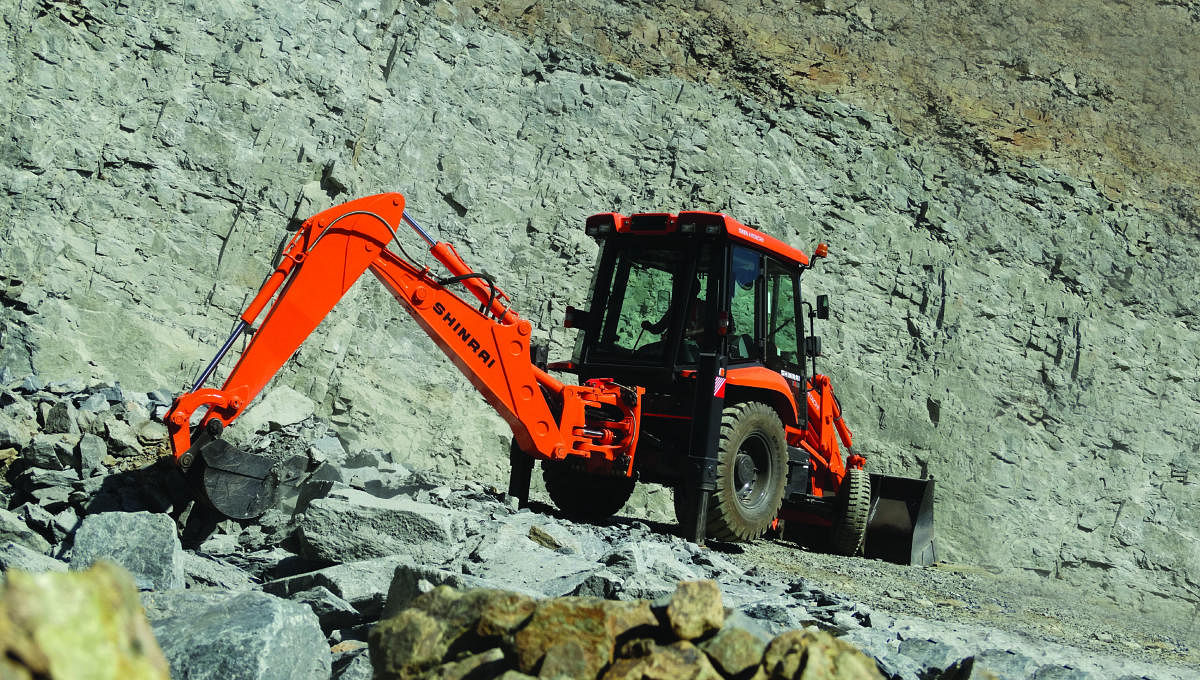 A backhoe loader of Tata Hitachi is in action at a quarry