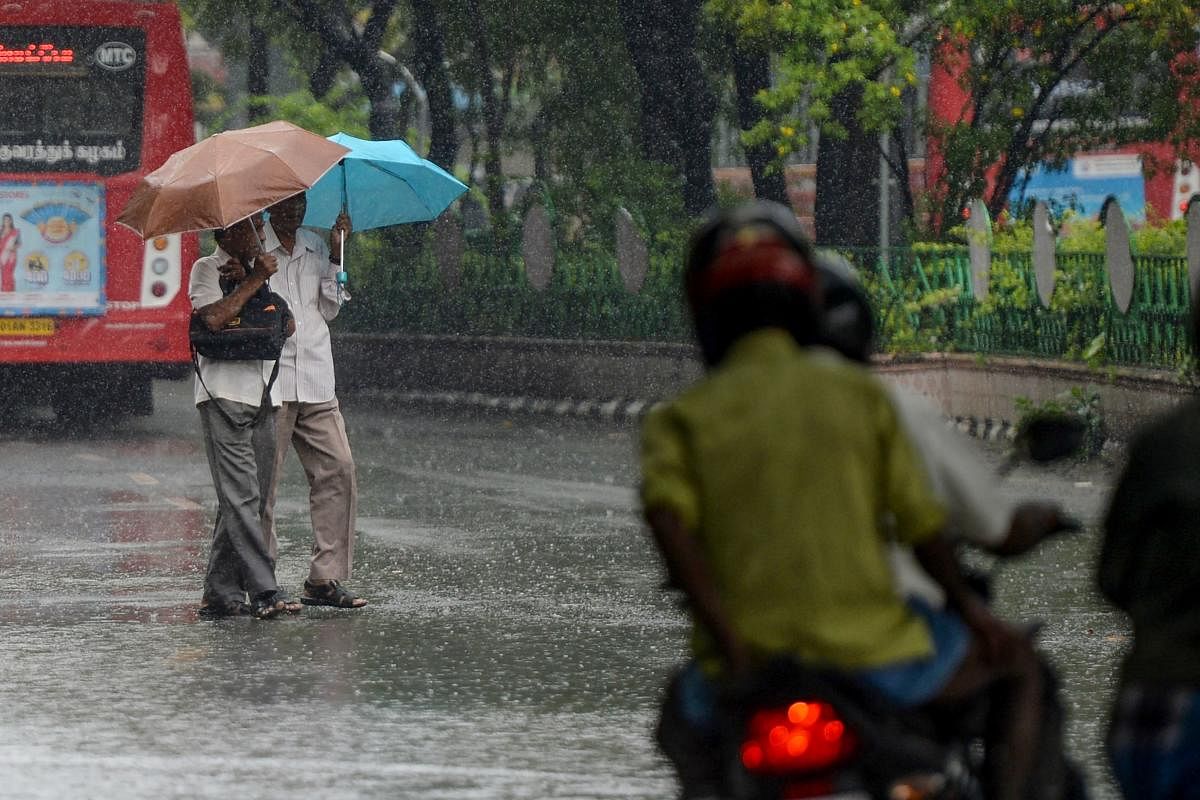 Pedestrians holding umbrellas cross a road during heavy rain in Chennai (AFP Photo)