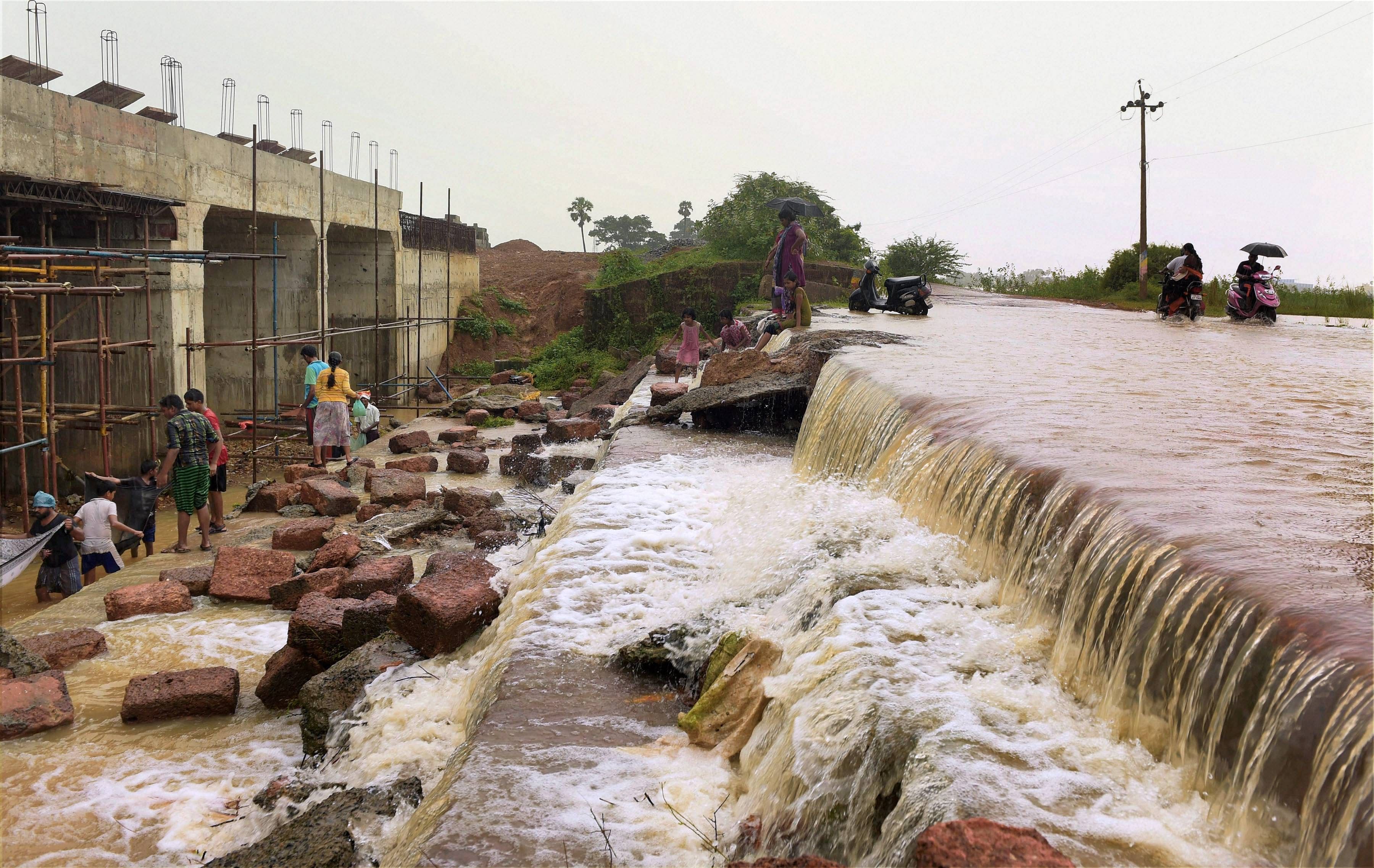 People trying to catch fish after a compound wall collapsed in neighbouring Redhills following heavy rainfall in Chennai. (PTI Photo)