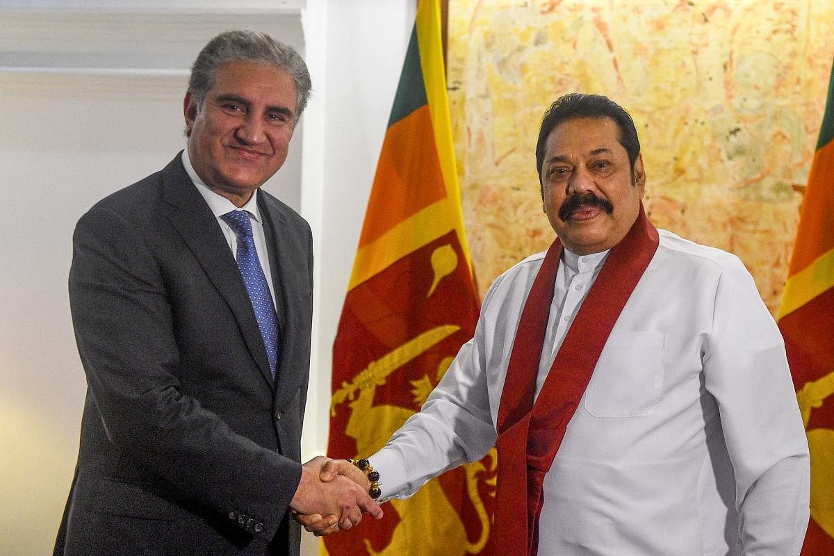 Sri Lanka's Prime Minister Mahinda Rajapaksa (R) shakes hands with Pakistan's Foreign Minister Shah Mehmood Qureshi. (AFP Photo)