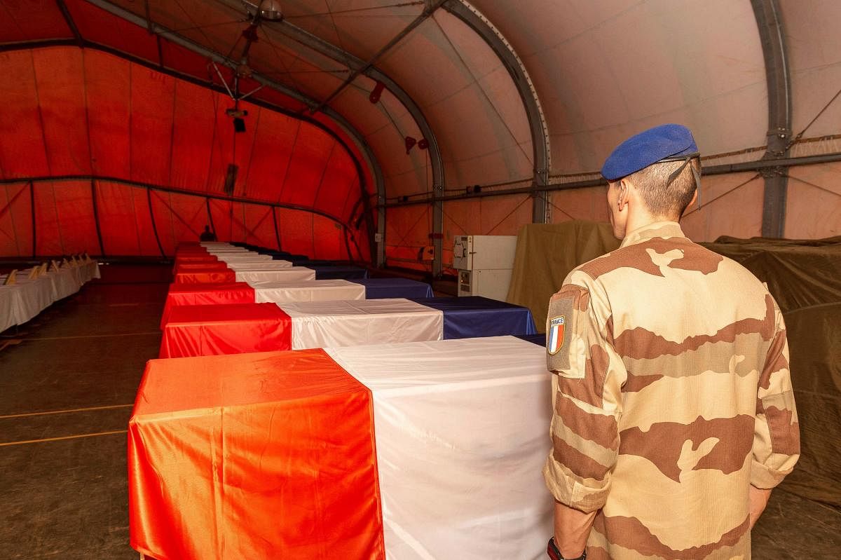 A French military of the Barkhane Force stands in front of the coffins of the 13 French soldiers. AFP photo