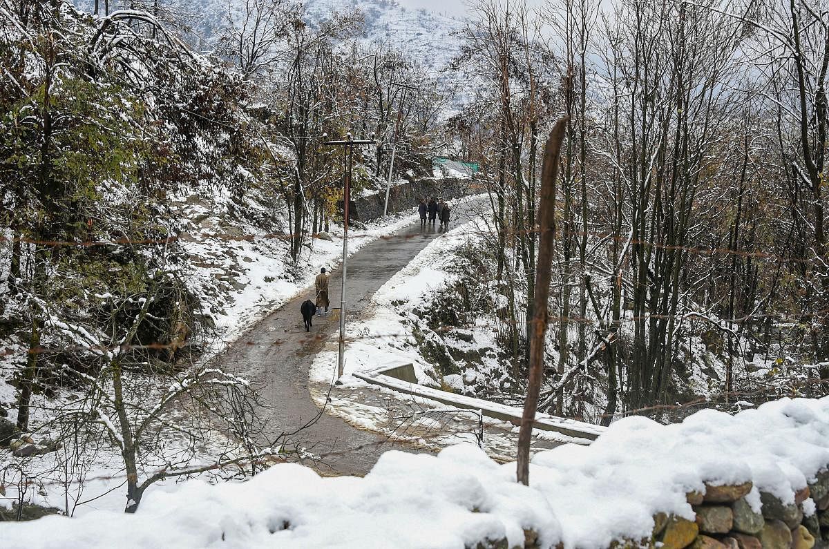 Pedestrians walk along a snow-laden hillside following light snowfall, on the outskirts of Srinagar, Thursday, Nov. 28, 2019. (PTI Photo)