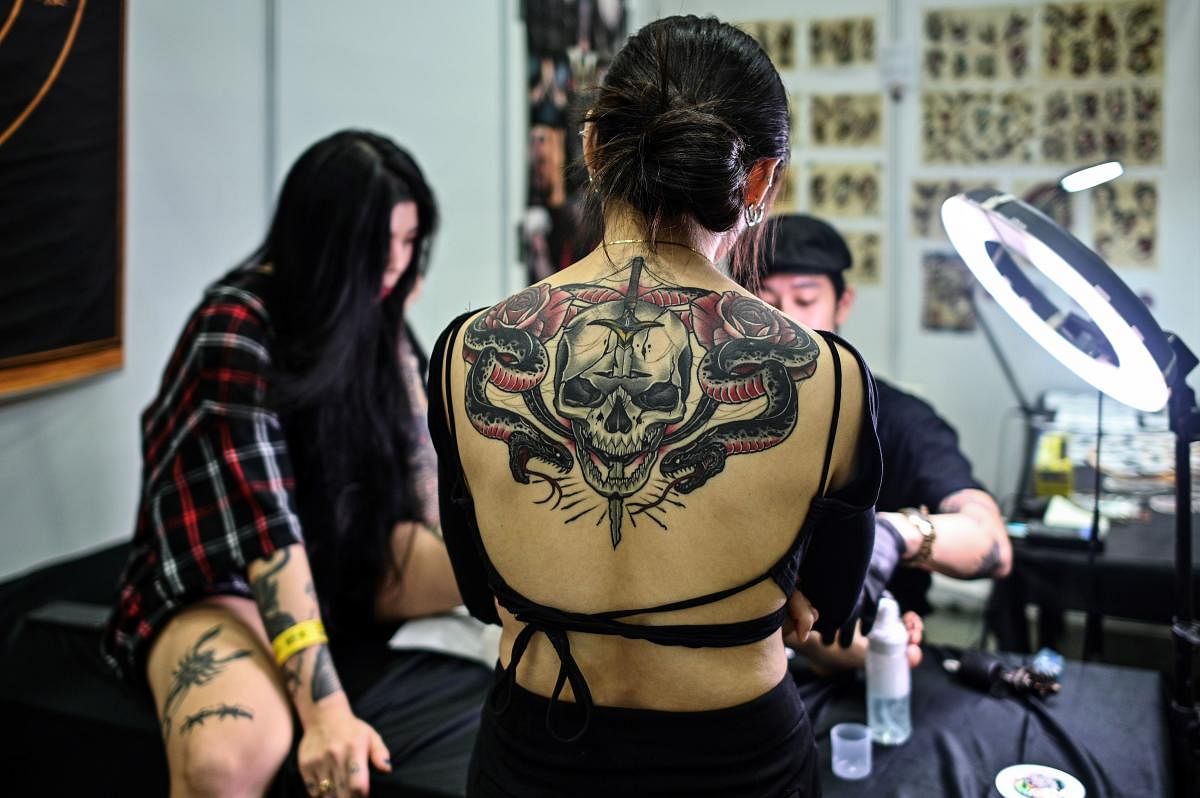 A woman with tattoo watches an artist working during the International Malaysia Tattoo Expo in Kuala Lumpur. AFP photo