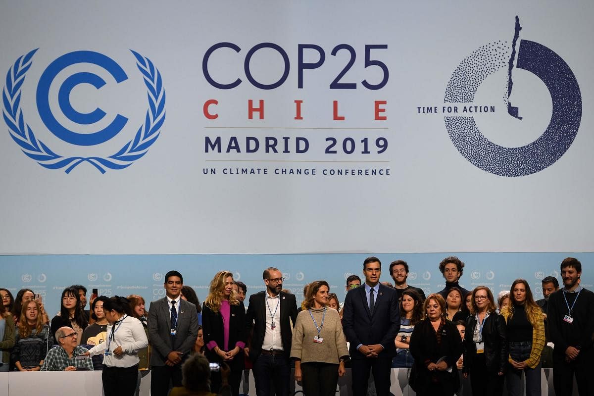 Spanish Prime Minister Pedro Sanchez (C-R) and Spanish Minister for Ecological Transition Teresa Ribera (C-L) pose with volunteers onstage as they visit the congress centre IFEMA in Madrid on November 30, 2019, where the COP25 climate summit will be held