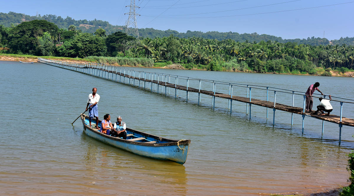 Residents of Pavoor-Uliya cross River Nethravathi through a boat.