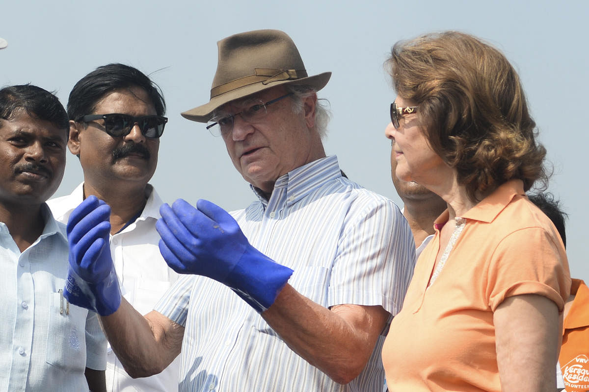 Sweden's King Carl XVI Gustaf (C) speaks with with volunteers as Queen Silvia (R) looks on as they participate in a beach clean-up project a the Versova Beach in Mumbai on December 4, 2019. (Photo by Punit PARANJPE / AFP)