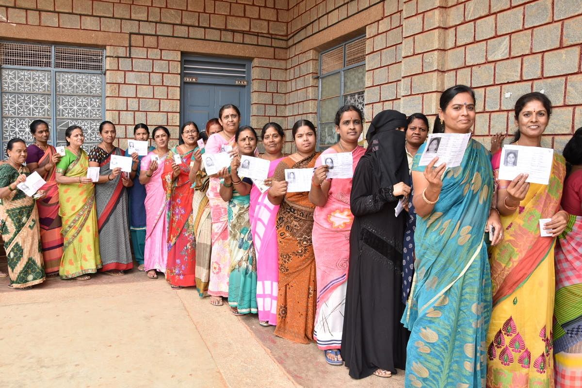 Women wait for their turn to exercise franchise at a polling booth in Chikkaballapur on Thursday. DH Photo