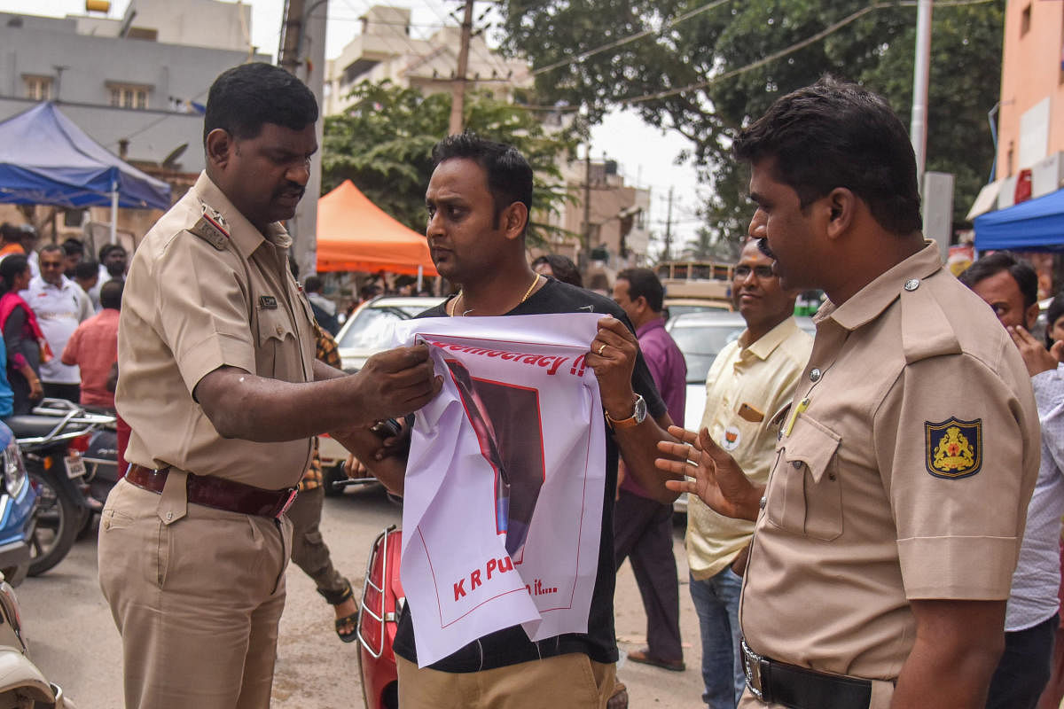 Police confront activist Santosh Raj with his banner outside a polling booth on Thursday.