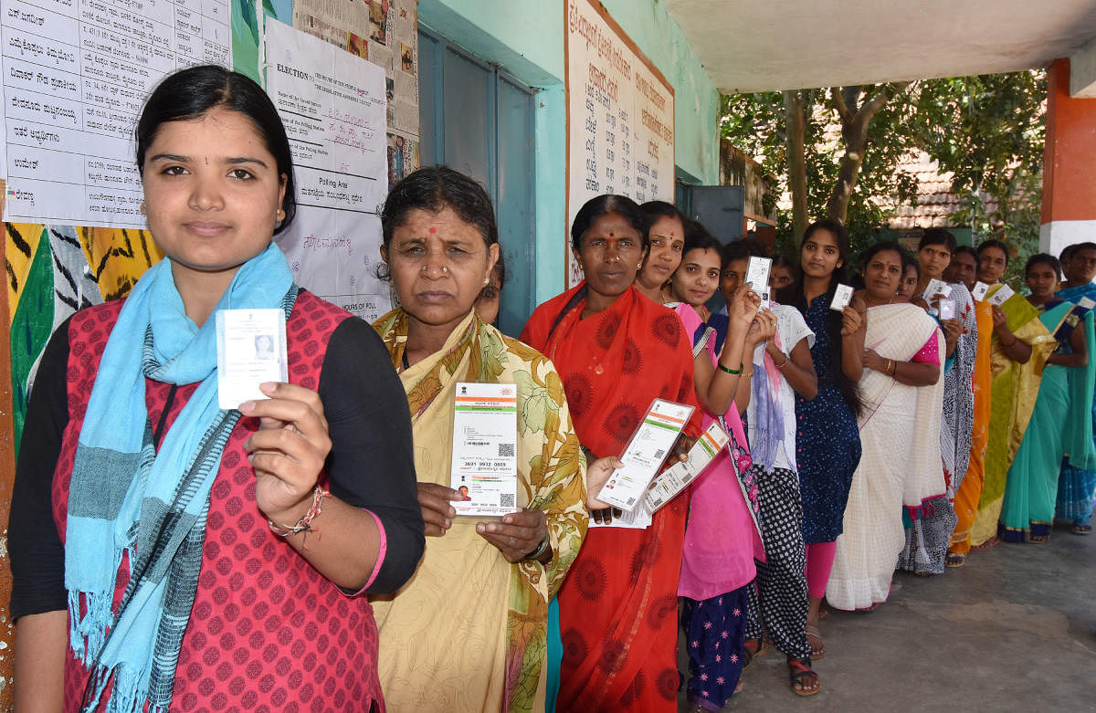 Women wait in queue to cast their votes at a polling centre, in Hunsur taluk, Mysuru district on Thursday. Dh-file photo