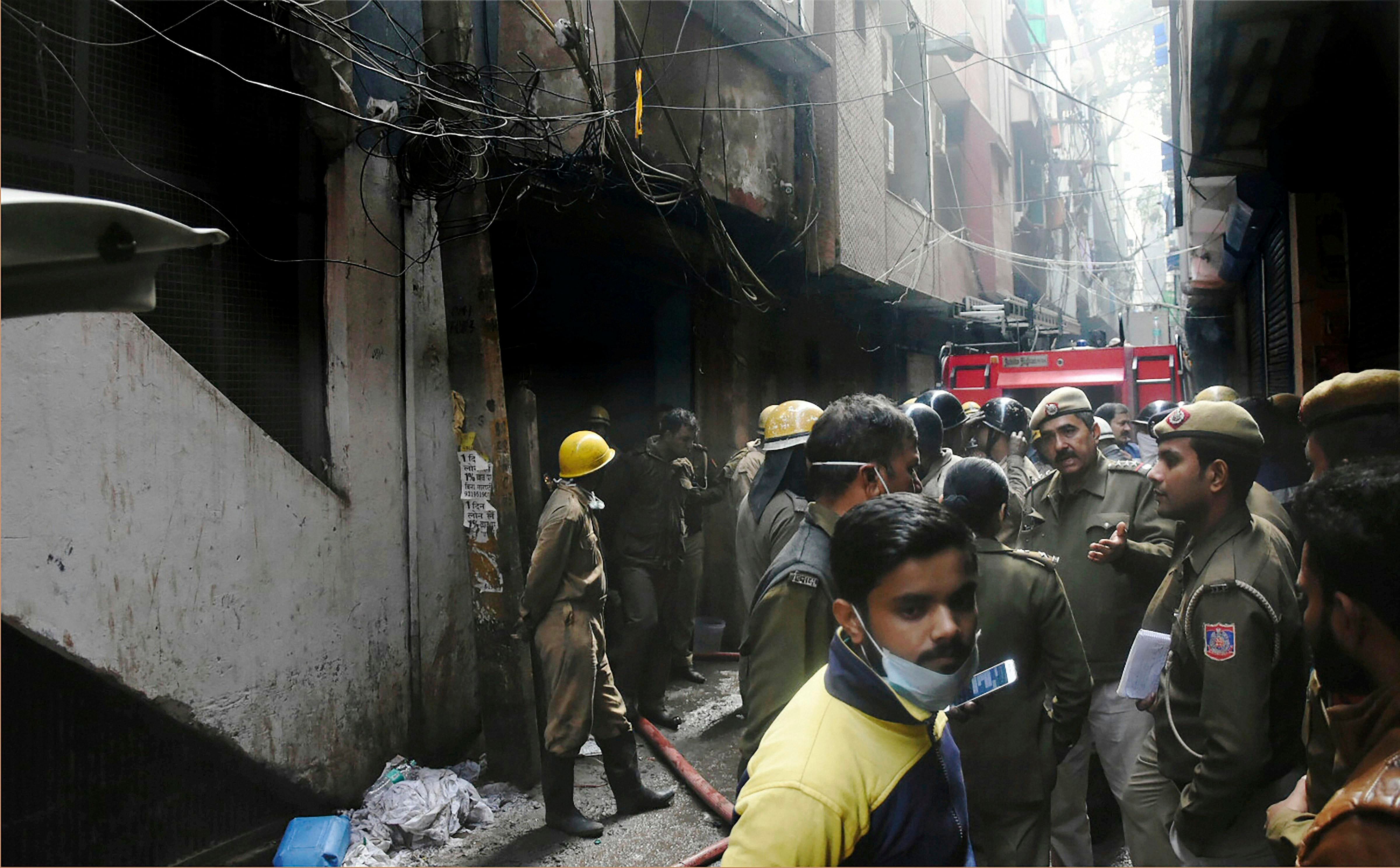 Police personnel and firefighters at the site of a fire in a factory at Rani Jhansi Road, in New Delhi. (PTI Photo)