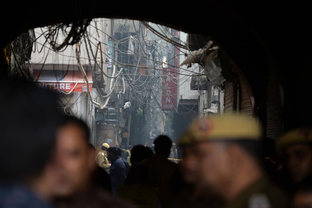 Police personnel block a street leading to a factory site after a fire broke out, in Anaj Mandi area of New Delhi. AFP