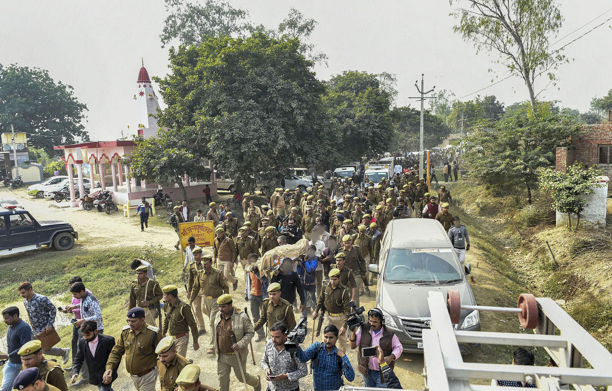  Police personnel march as family members and relatives carry the mortal remains of Unnao rape victim for burial. PTI