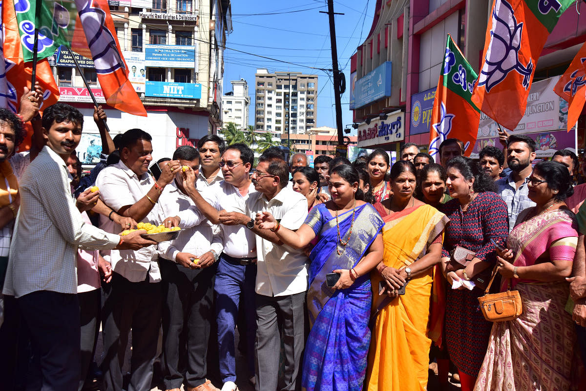 BJP workers celebrate the BJP's victory in byelection by distributing sweets outside BJP office in Mangaluru on Monday. DH Photo
