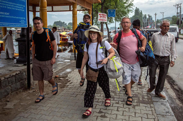 Foreign tourists carry their luggage as they walk on the banks of Dal Lake before leaving Srinagar August 3, 2019. (Reuters photo)